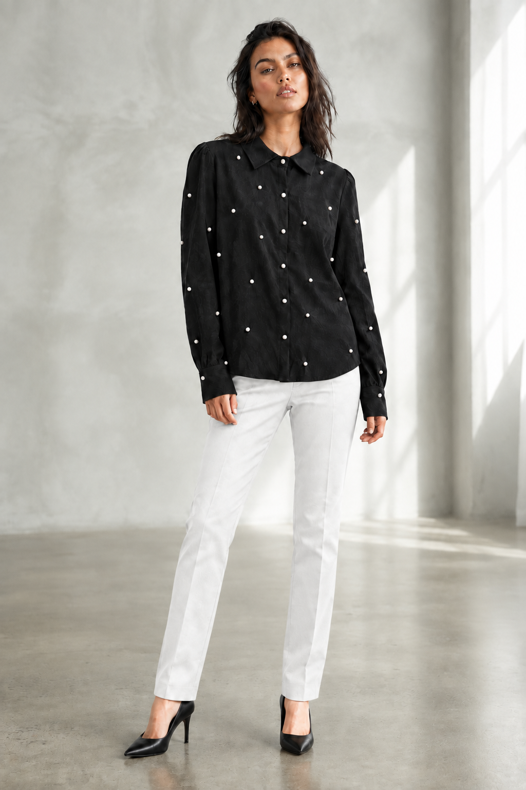 Model wearing the black embellished blouse with white pants and black heels